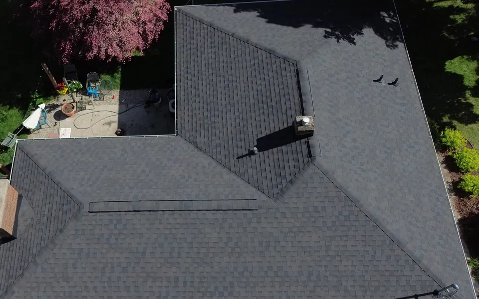 Aerial view of a dark shingle roof, ridge, chimney and intersecting roof planes